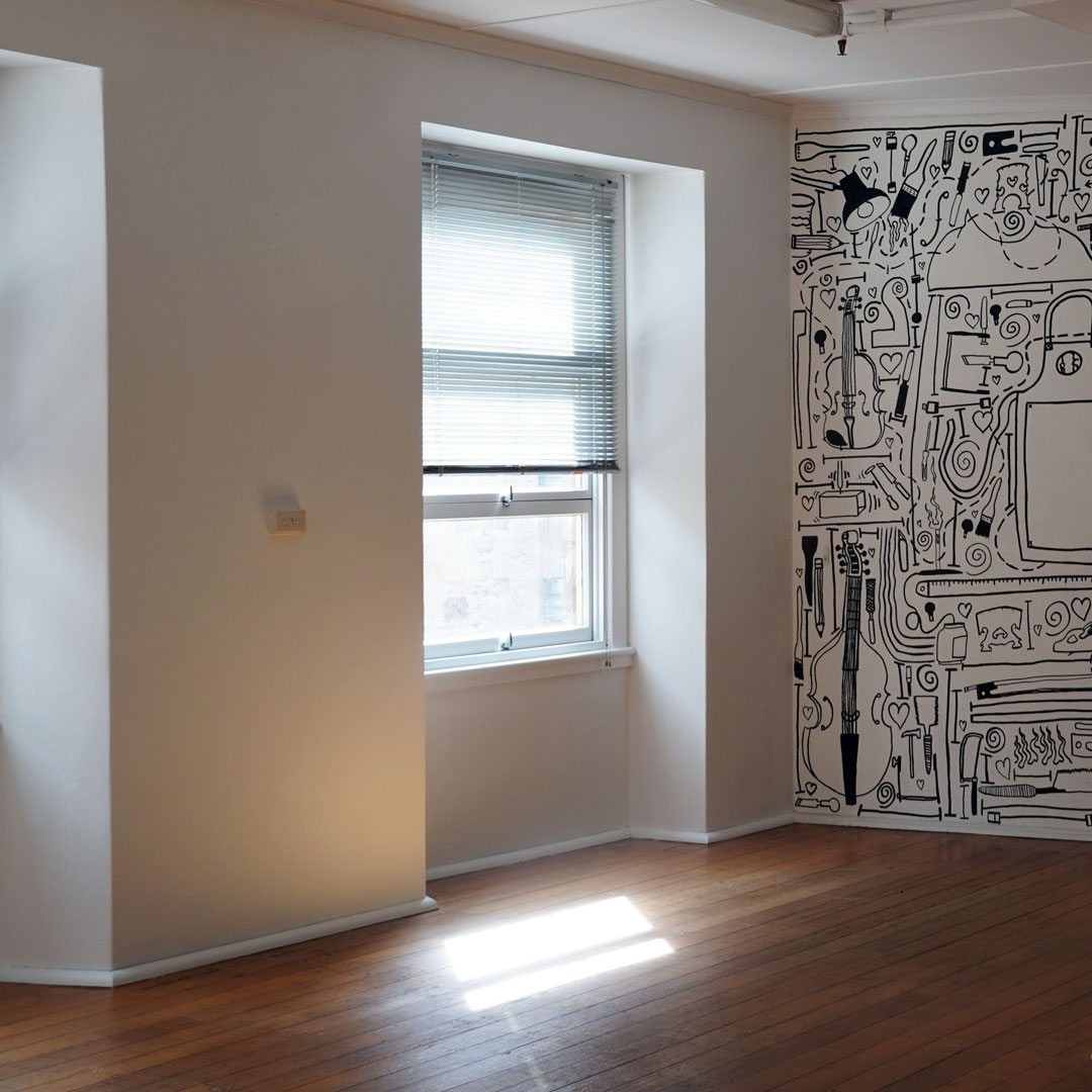 An artist's studio empty of furniture and a mural on the wall