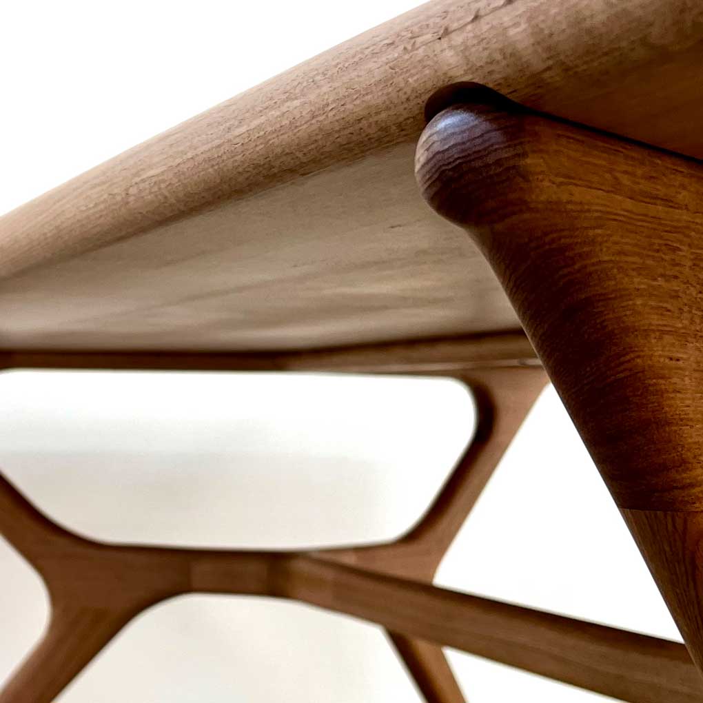 A close up of the corner and underside of a dining table made from Tasmanian oak, against a white background.