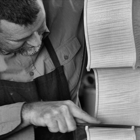 A black and white photo of the artist Philip Smith carving an instrument