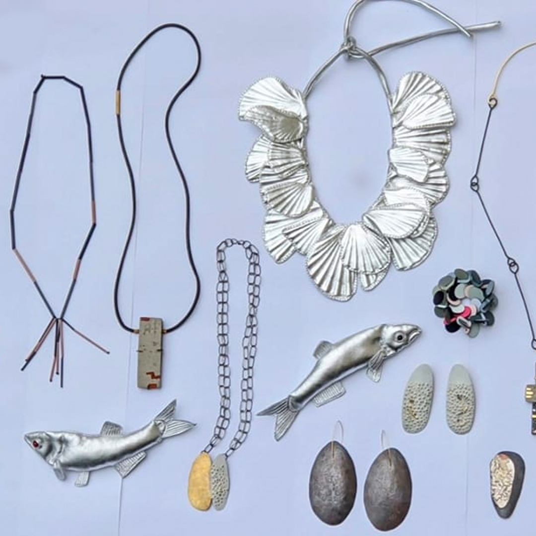 A grouping of contemporary jewellery sits on pale blue background. Made by the artists that work out of State of Fluxa