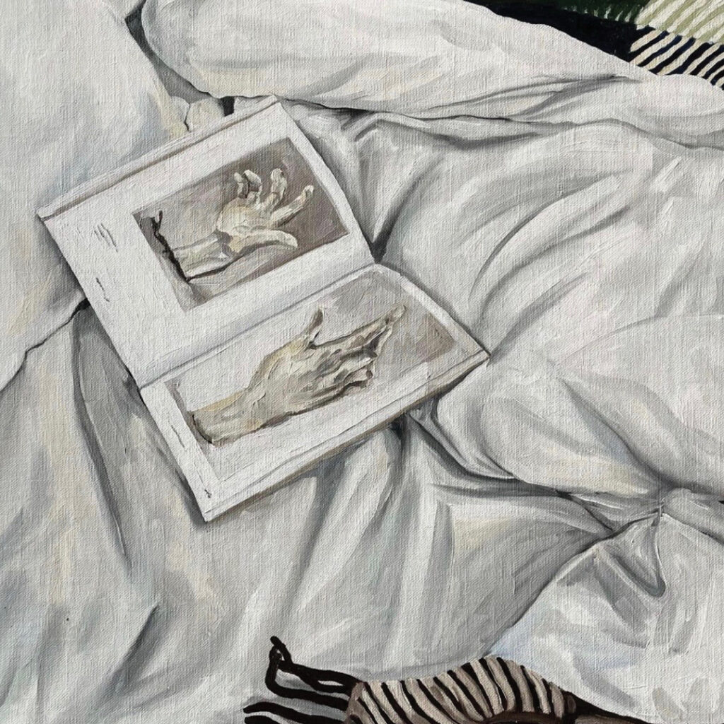 An open book, with two sketches of hands, lying on a heap os crumpled white sheets. In the corners of the painting there are fragments of striped fabric.