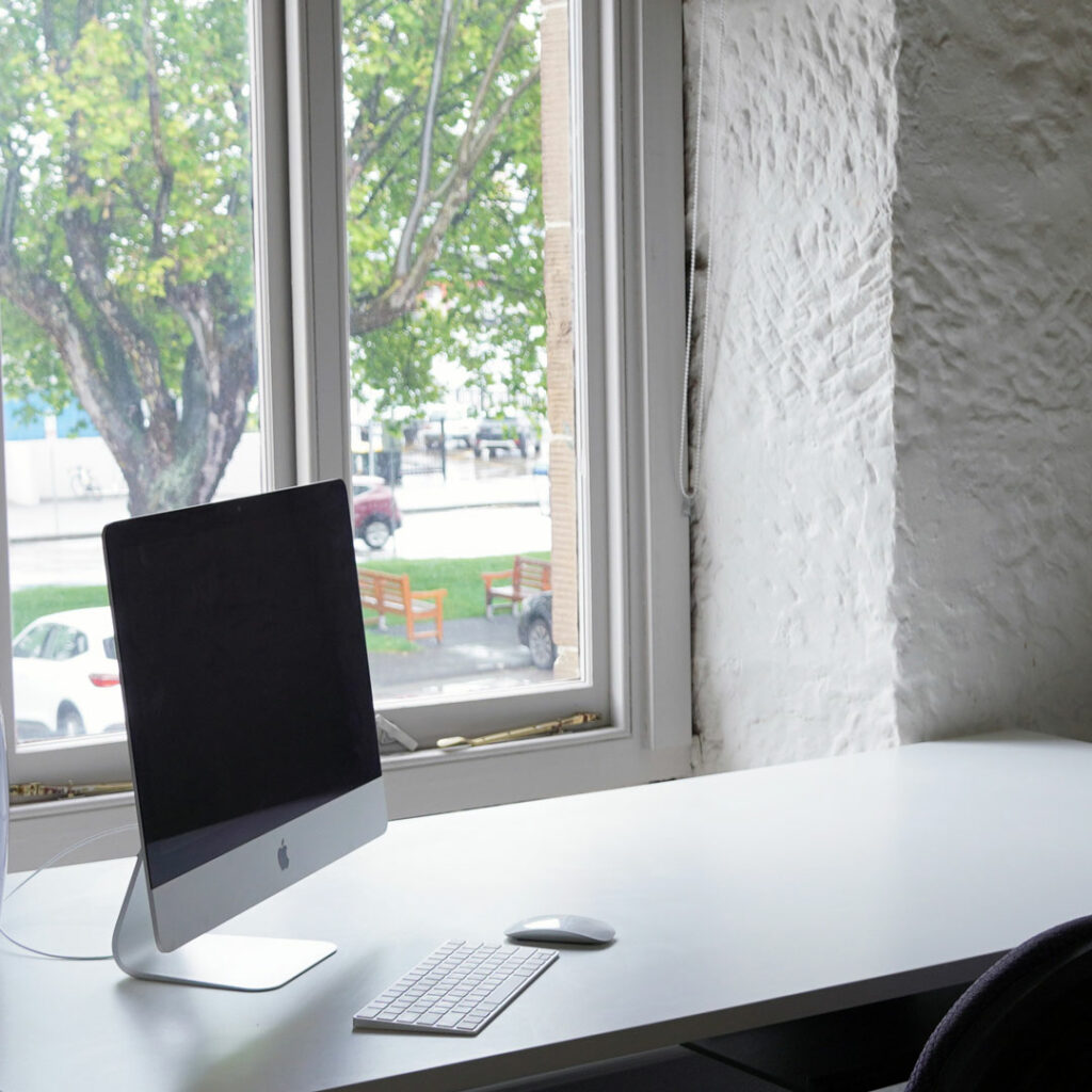A desk with a computer by a window looking onto Salamanca place