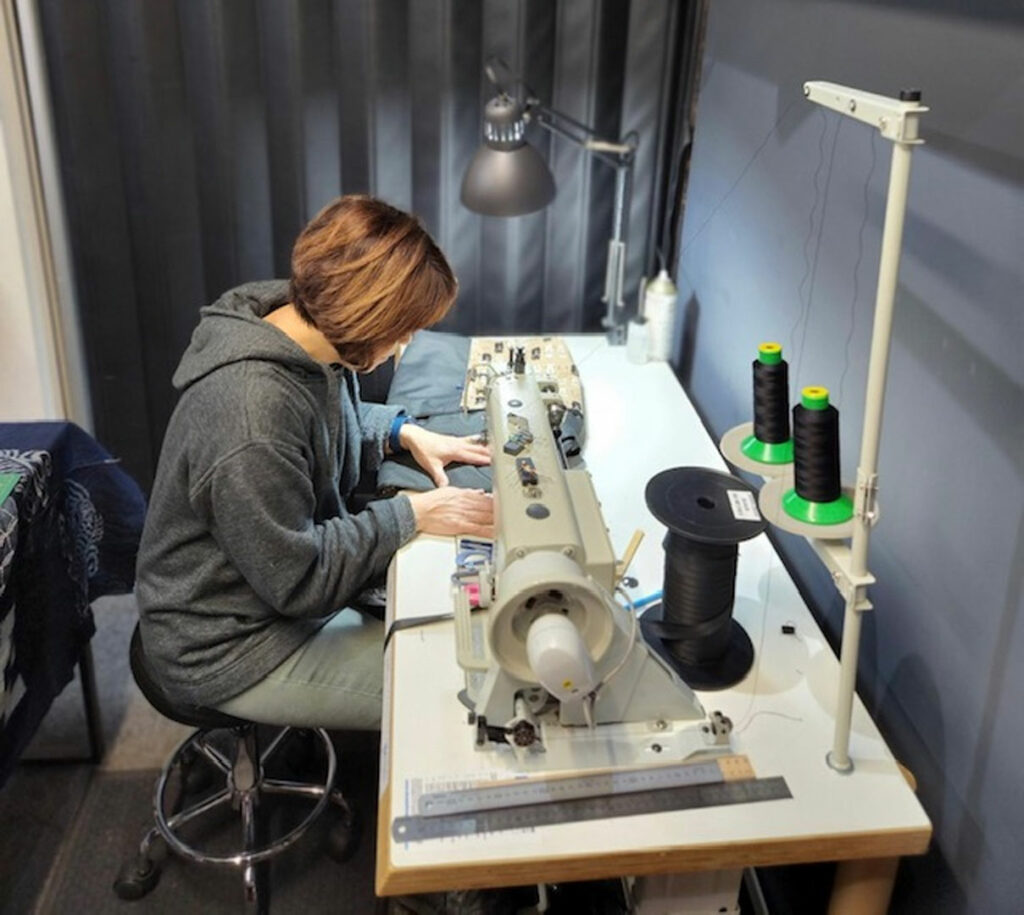 The designer making the handbags and purses using a machine at a desk